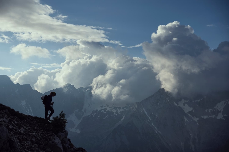 Silhouette of an athlete ontop of a high alpine traverse against the clouds